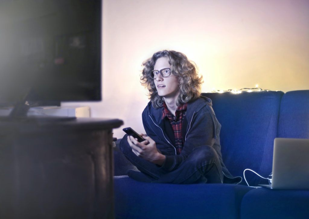 a schoolboy watches school tuitions on television at home.