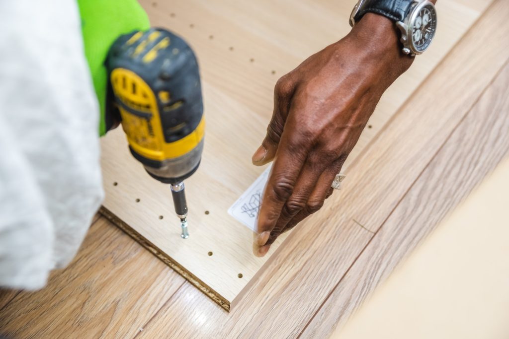 A student is drilling a screw into a wooden plank.