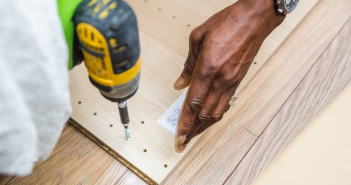 A student is drilling a screw into a wooden plank.